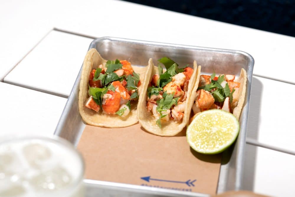 tray of three #bartacosecret lobster tacos with a lime wedge garnish