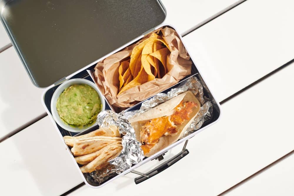 interior image of the bartaco kids lunch box with a kids tray (a quesadilla, guac + chips, and your choice of taco) served inside