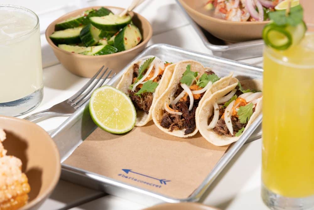 table with tray of three #bartacosecret tacos plus sides + drinks