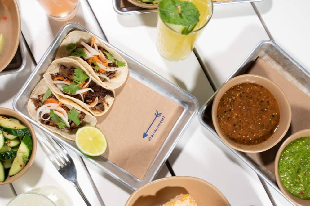 table with variety of not tacos, drinks + a tray of #bartacosecret brisket tacos